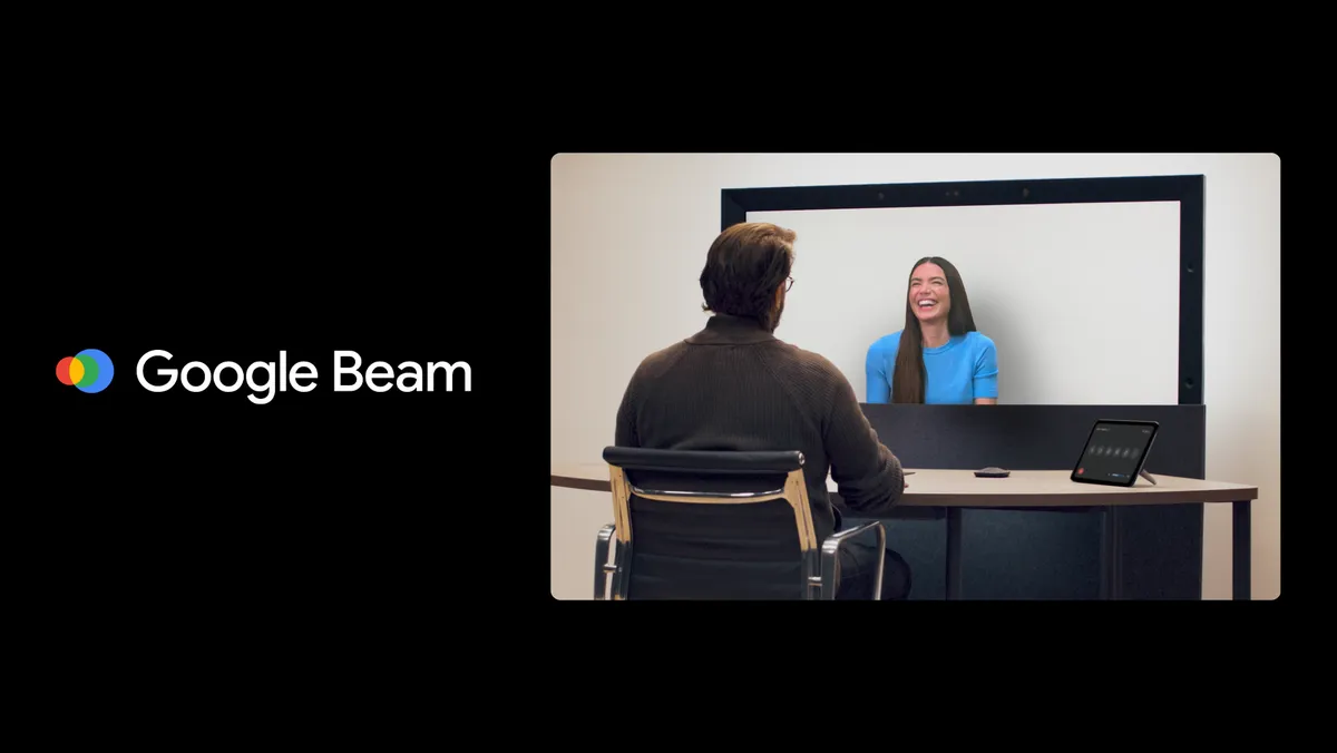 Two people connect on Project Starline. The person on the screen is smiling at the person in the foreground.