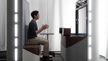 A persons sits in a booth using Project Starline on a call.