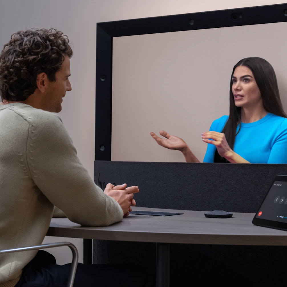 A person is looking at a Beam display. The person on the screen of the Beam display is visible and gesturing.